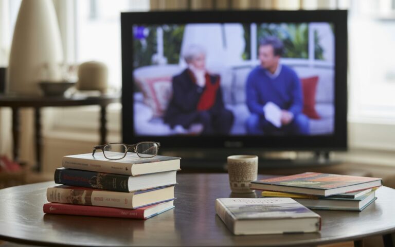 Salon ensoleillé, livres et télé floue.