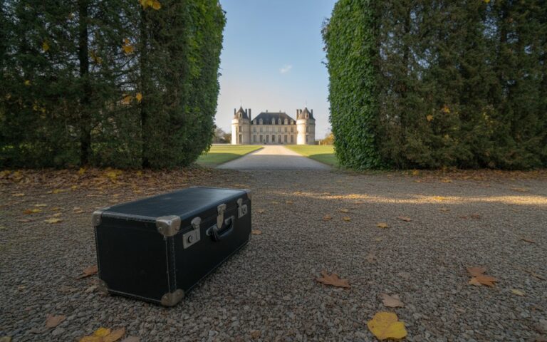 Allée de château avec valise et feuilles