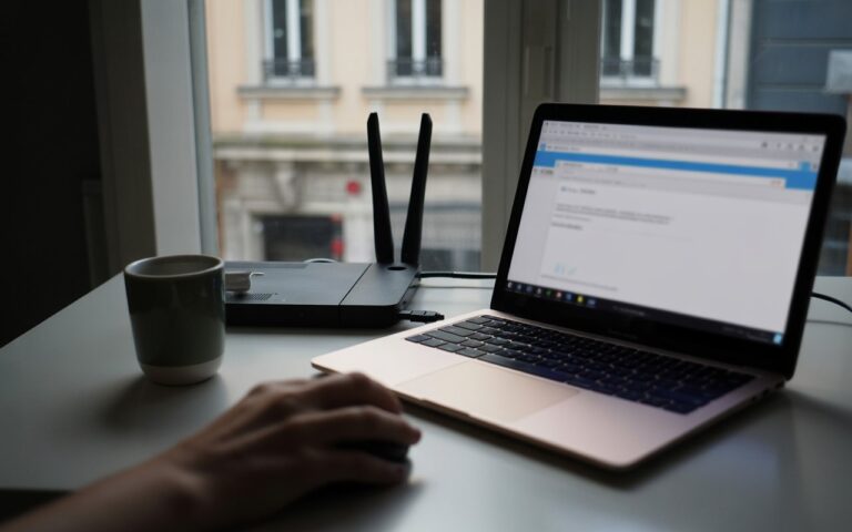 Bureau nuit, ordinateur flou, routeur et main.