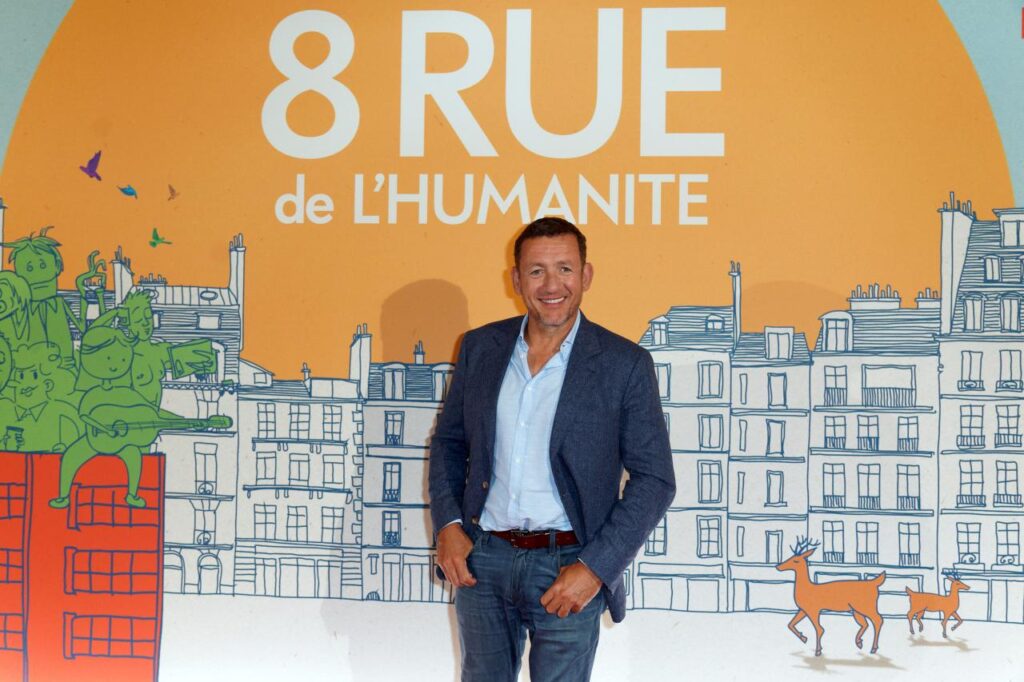 Dany Boon assis dans un décor élégant, illustrant sa réussite financière après le succès des Ch'tis