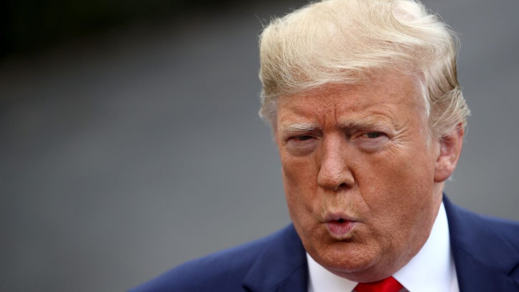 Donald Trump souriant en costume, symbole de sa richesse et de son image publique controversée