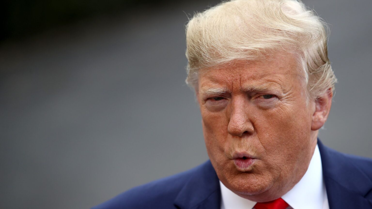 Donald Trump souriant en costume, symbole de sa richesse et de son image publique controversée