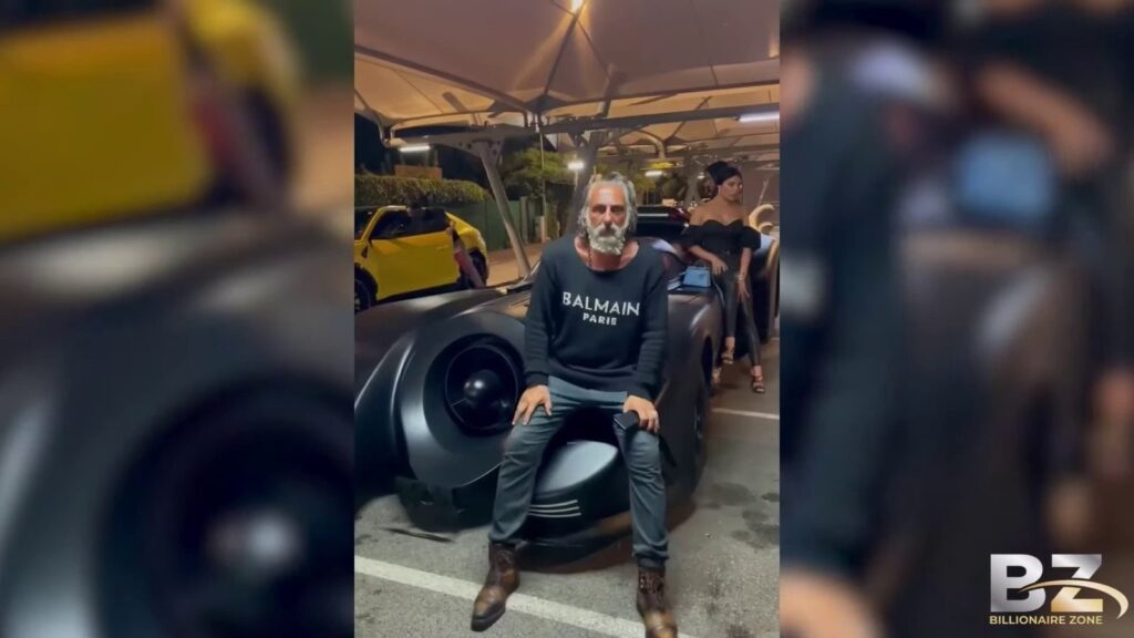 Ilan Tobianah, surnommé Zeus, posant devant des voitures de luxe illustrant sa fortune en 2024
