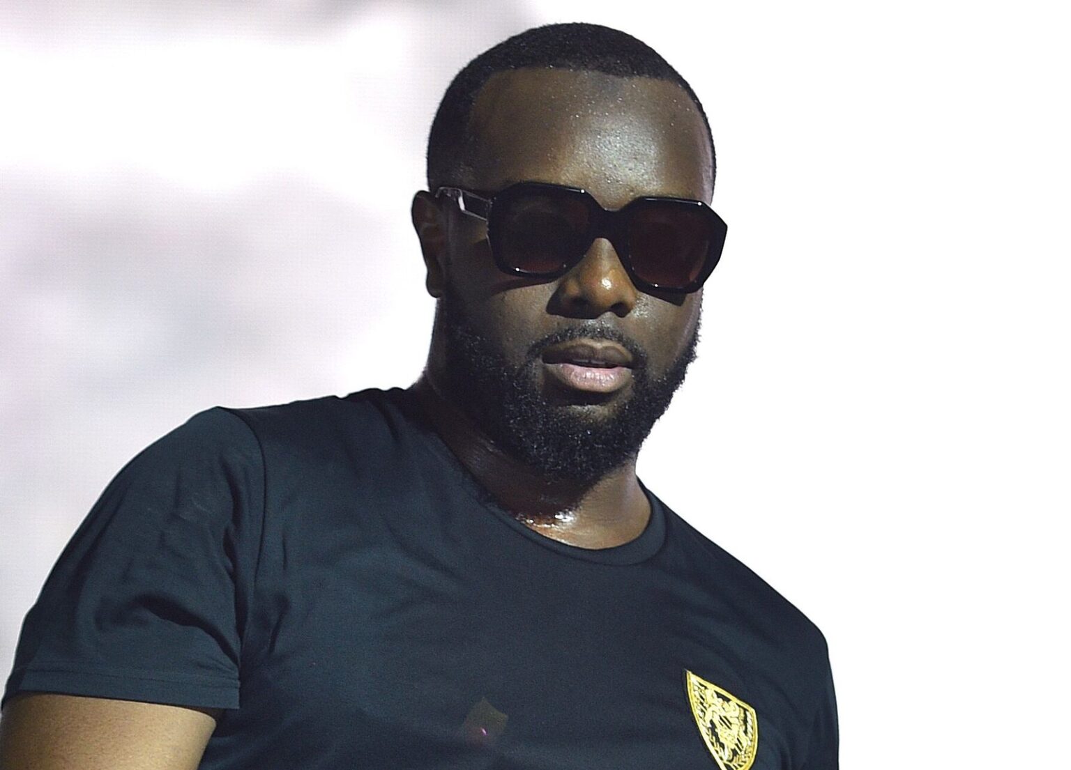 Maître Gims posant avec élégance, illustrant sa réussite financière et son image de star millionnaire