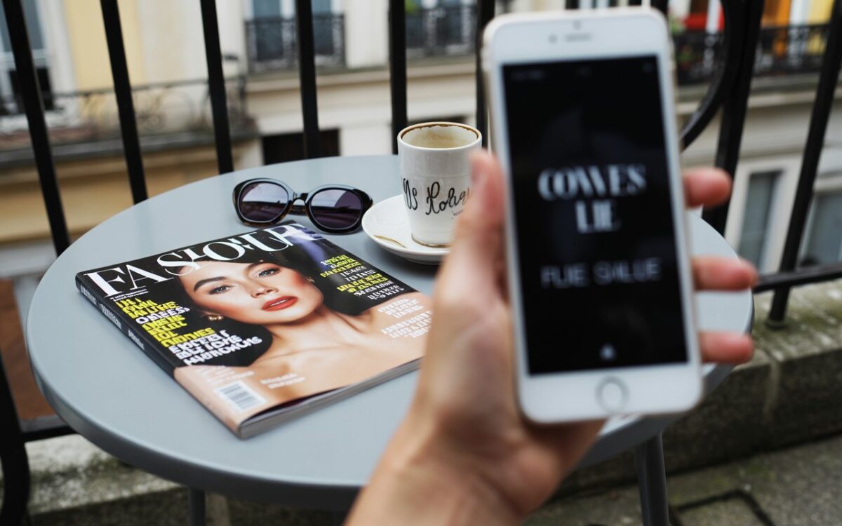 Balcon, magazine retourné, lunettes et téléphone flou.