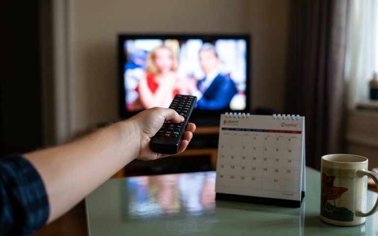 Main, télécommande, télé floue, calendrier et mug.